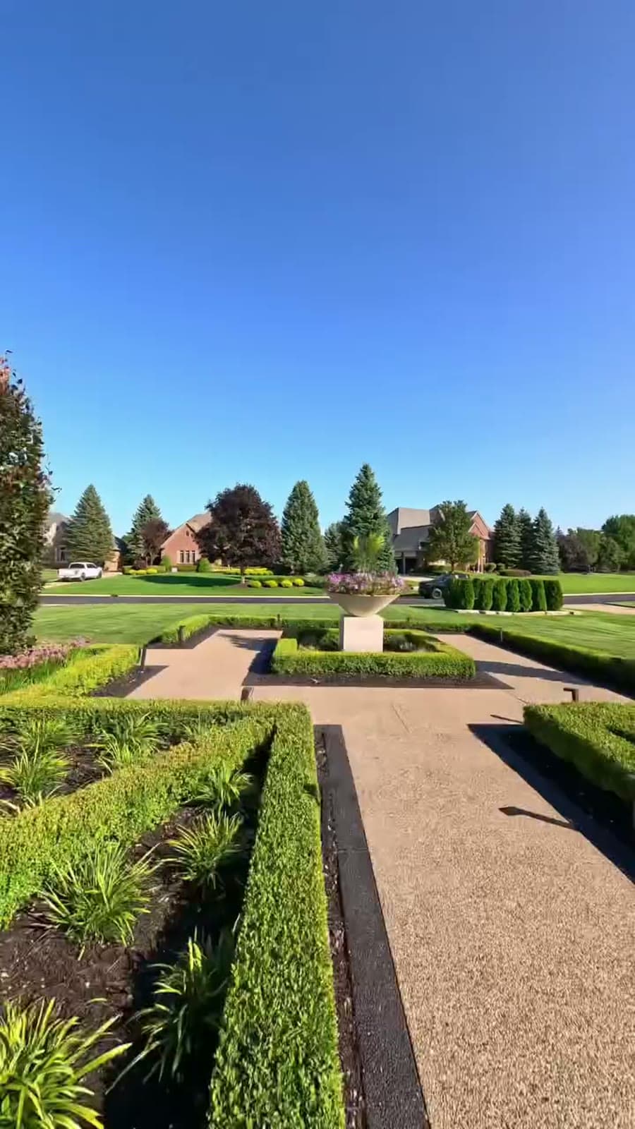 Manicured formal gardens leading to a large home